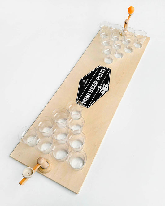 leseni prenosni mini beer pong komplet, diagonalna slika,prazni kozarci in oranžna žogica v desnem katapultu, prikazuje leseni beer pong set, v sredini nalepka mini beer pong, hoplales.