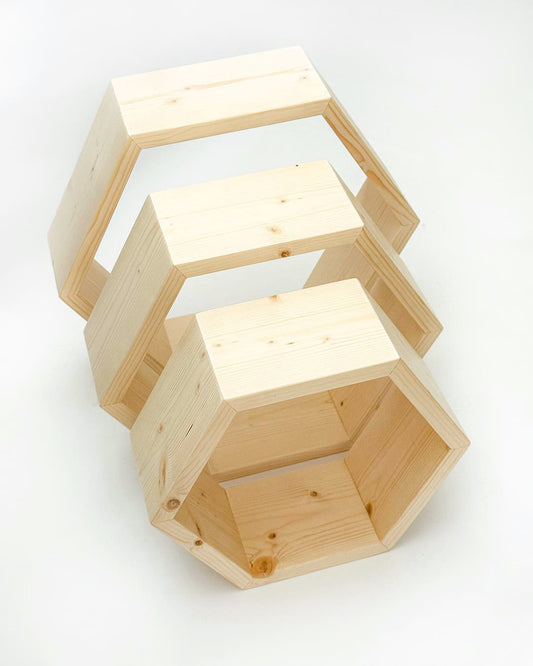 Tri lesene sataste police v različnih velikostih, z naravno leseno teksturo, postavljene ena na drugo v moderni obliki.