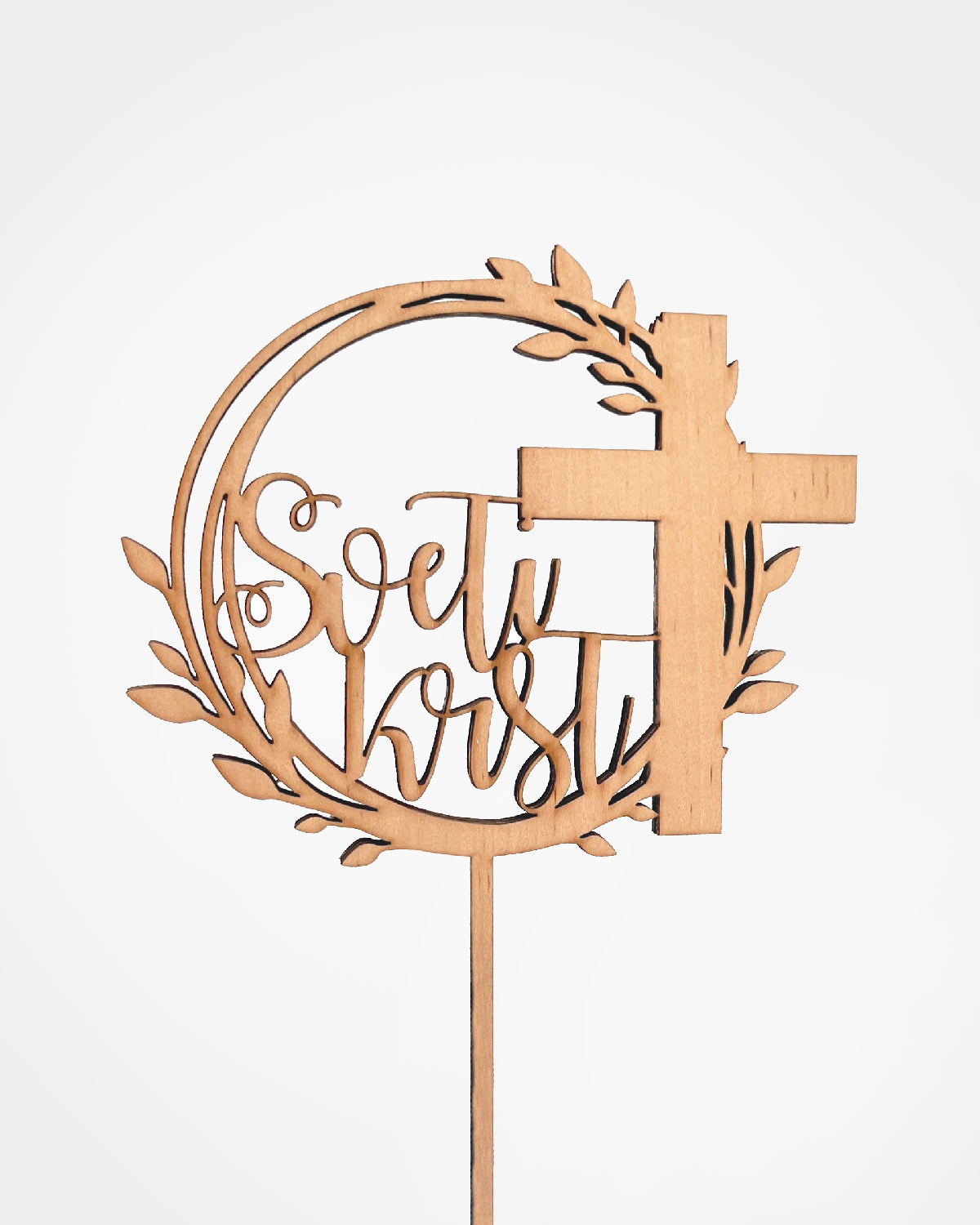 topper ali napis za torto sveti krst. Toper je na sredini bele visoke torte. Je iz temnega furnirja. Na toperju je desno velik križ, levo pa piše sveti krst. Vsaka beseda je v svoji vrstici. Toper za torto sveti krst.