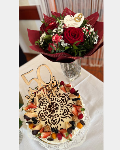 Topper za torto, napis za torto, 50 skupnih let, topper za zlato poroko. topper za zlatoporočenca. Leseni toper 50 skupnih let na beli podlagi z zlatimi packami. Velik toper. V ozadju šopek z lesenim srcem in napisom zlata poroka.