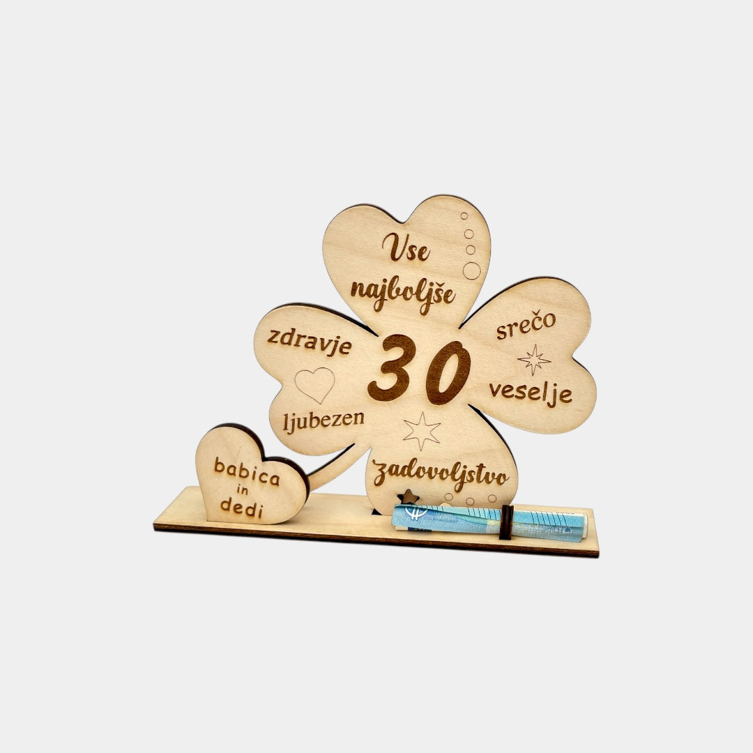 Lesena voščilnica deteljica. Vse najboljše. Voščilnica za 30 let. Gor piše Vse najboljše, srečo, veselje, zadovoljstvo, zdravje, ljubezen. V srčku je podpis babica in dedi. Voščilnica je tudi za denar. Pred deteljico je zavihanih 20 eur.