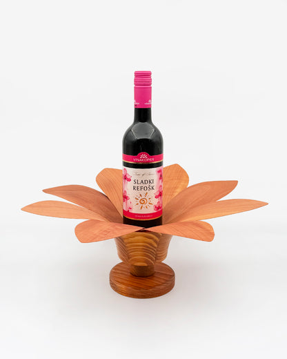 Lesena roža za vino s podstavkom. V sredico je postavljena steklenica sladkega refoška. Lahko je tudi kakršnokoli drugo vino. Cvetlica, roža je temno rjave barve.