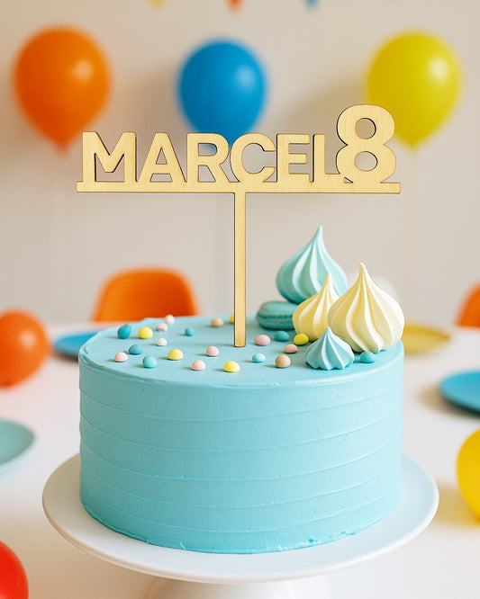Na sliki je turkizna torta s topperjem oz napisom iz lesa. Na palici je ime Marcel in številka 8