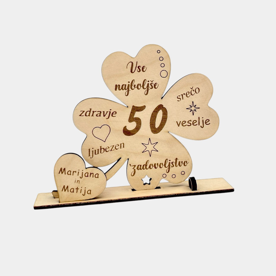 Lesena voščilnica v obliki deteljice. Vse najboljše. Voščilnica za denar. Gor piše še srečo, veselje, zadovoljstvo, ljubezen, zdravje. Gravirano je srce, zvezda, krogci. Zraven je še srce v katerem je podpis. Zraven je prostor za denar, ki se zaviha in zatakne v krogec.